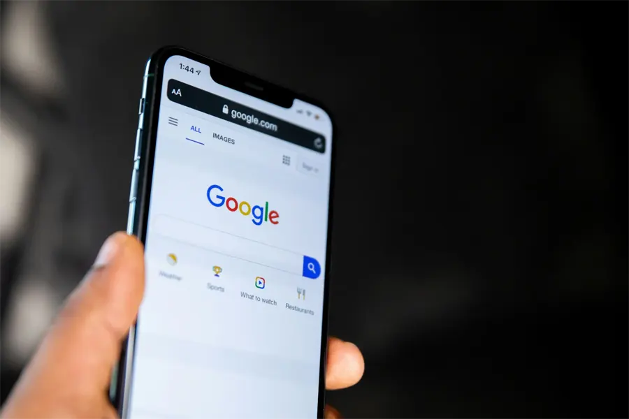 Hand holding a phone showing the Google search page
