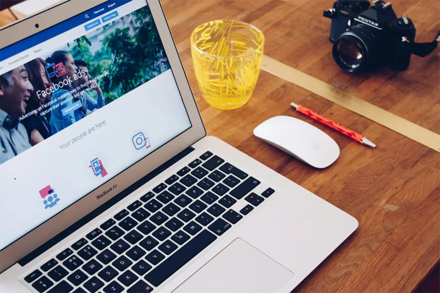 Laptop displaying Facebook ads and social media icons illustrating SEO versus PPC for Hampshire businesses.