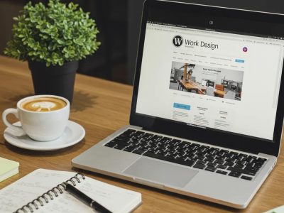 Modern workspace with laptop showing WordPress design, coffee, and notepad