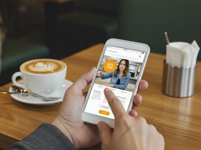 Person using a smartphone in a café, illustrating mobile-first website design principles